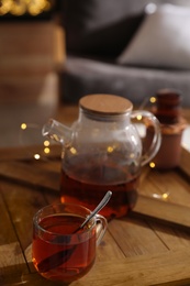 Photo of Teapot and cup with hot tea on table indoors