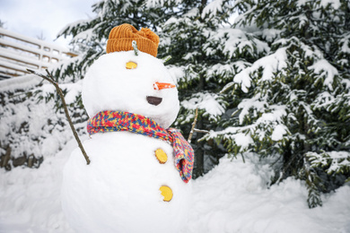 Photo of Funny snowman with hat and scarf outdoors. Winter vacation
