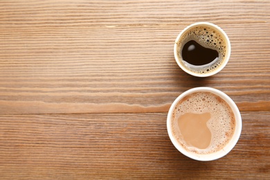 Photo of Cardboard cups of coffee on wooden table, top view. Space for text