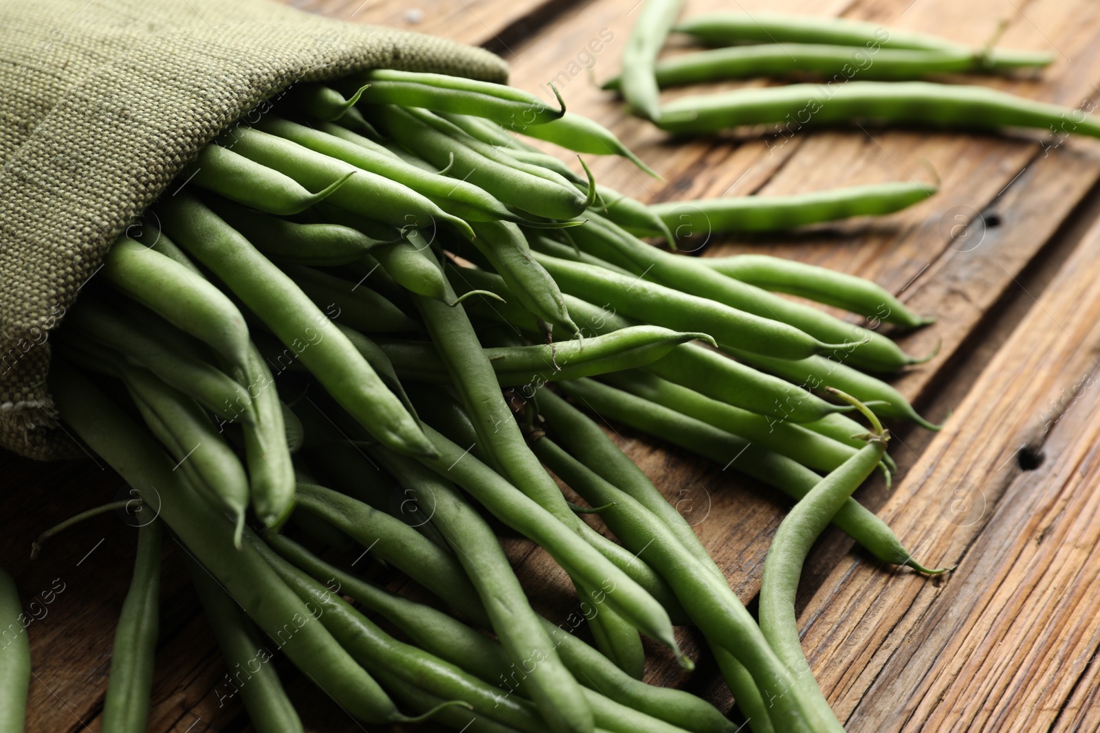 Photo of Fresh green beans in bag on wooden table, closeup