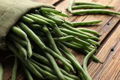 Photo of Fresh green beans in bag on wooden table, closeup