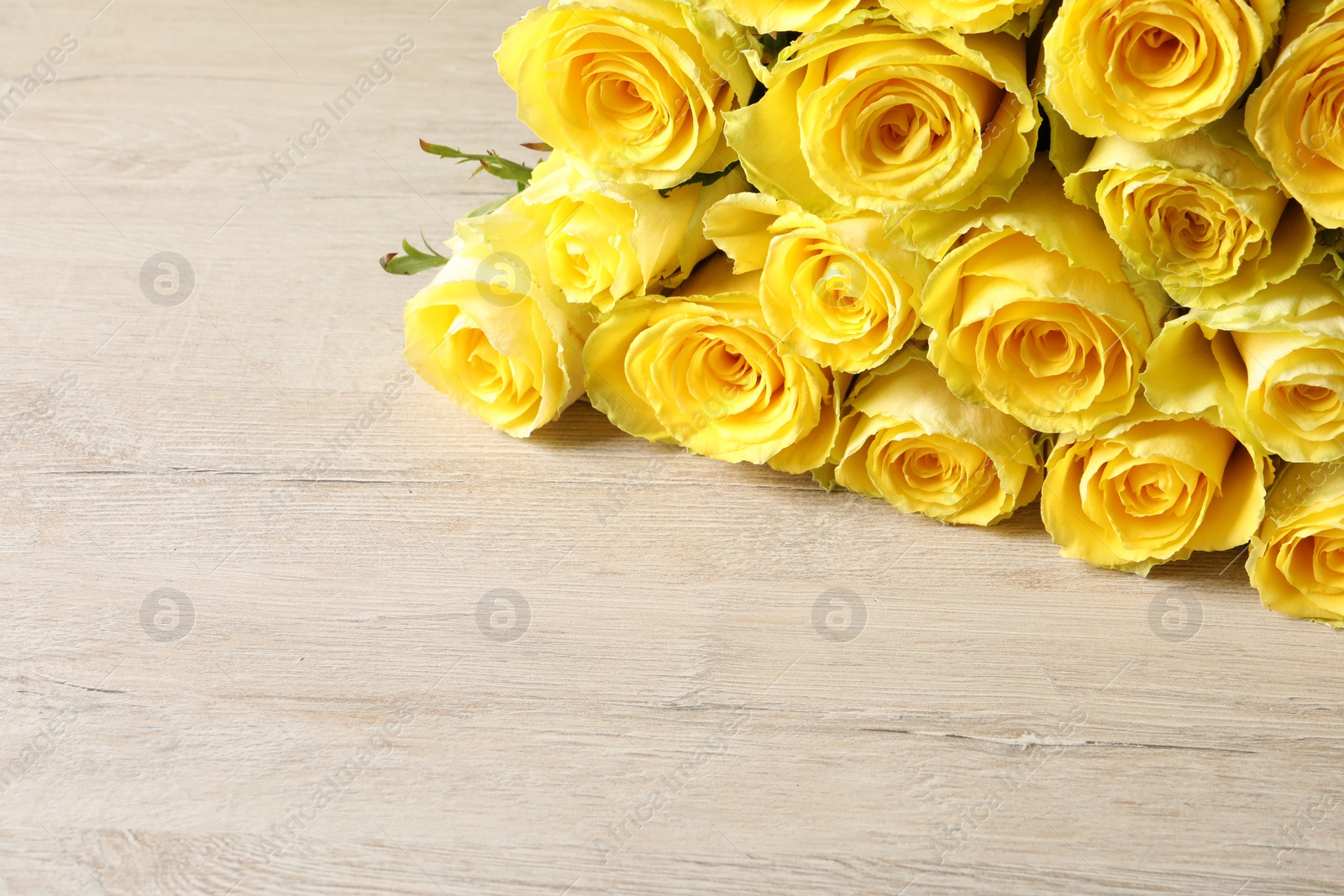Photo of Beautiful bouquet of yellow roses on wooden table, space for text