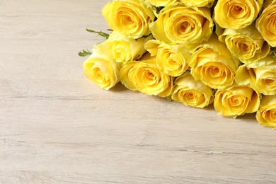 Beautiful bouquet of yellow roses on wooden table, space for text