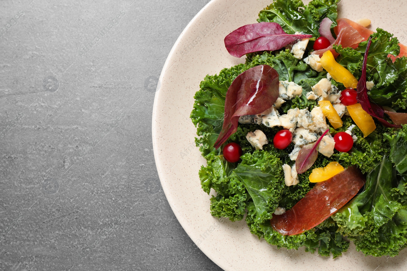 Photo of Tasty fresh kale salad on grey table, top view. Space for text