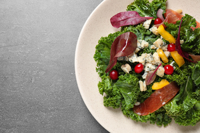 Photo of Tasty fresh kale salad on grey table, top view. Space for text