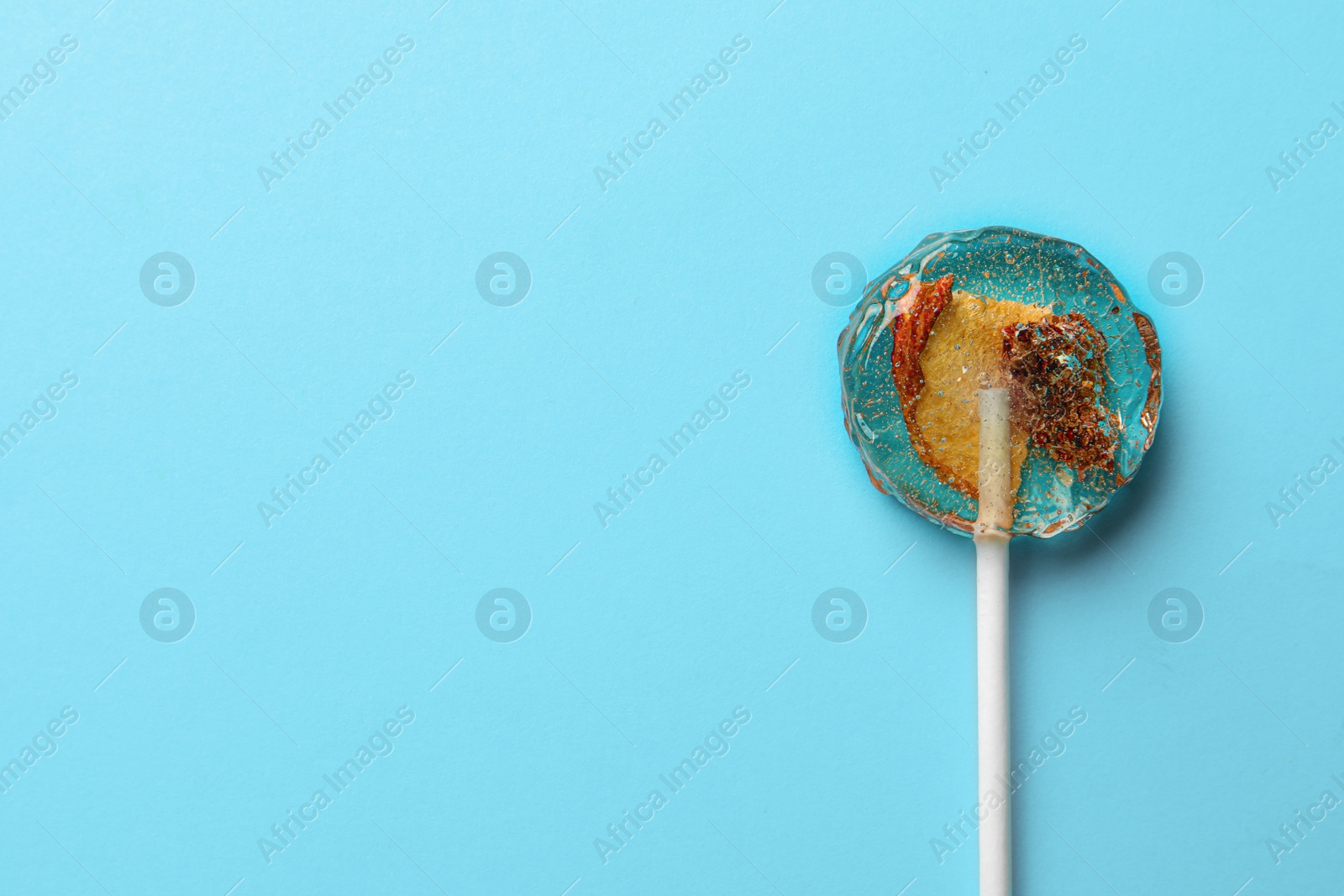 Photo of Sweet colorful lollipop with berries on light blue background, top view. Space for text