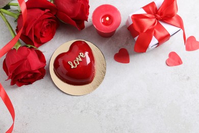 Photo of St. Valentine's Day. Delicious heart shaped cake, gift, roses and candle on light table, flat lay. Space for text