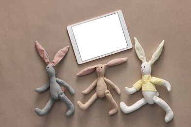 Photo of Modern tablet and kid's toys on light brown background, flat lay. Space for text