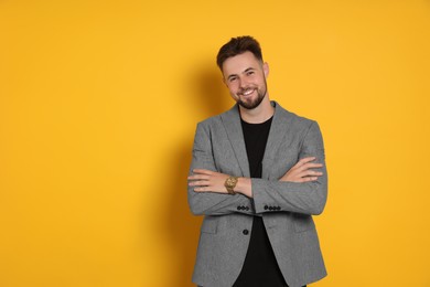 Photo of Handsome man in stylish grey jacket on yellow background, space for text