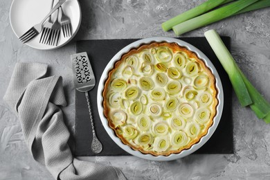 Photo of Freshly baked leek pie served on grey textured table, flat lay