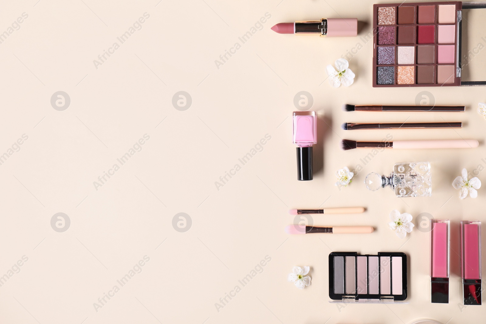 Photo of Flat lay composition with different makeup products and beautiful spring flowers on beige background, space for text