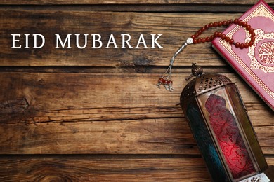 Image of Eid Mubarak greeting card. Arabic lantern, Quran and misbaha on wooden background, flat lay