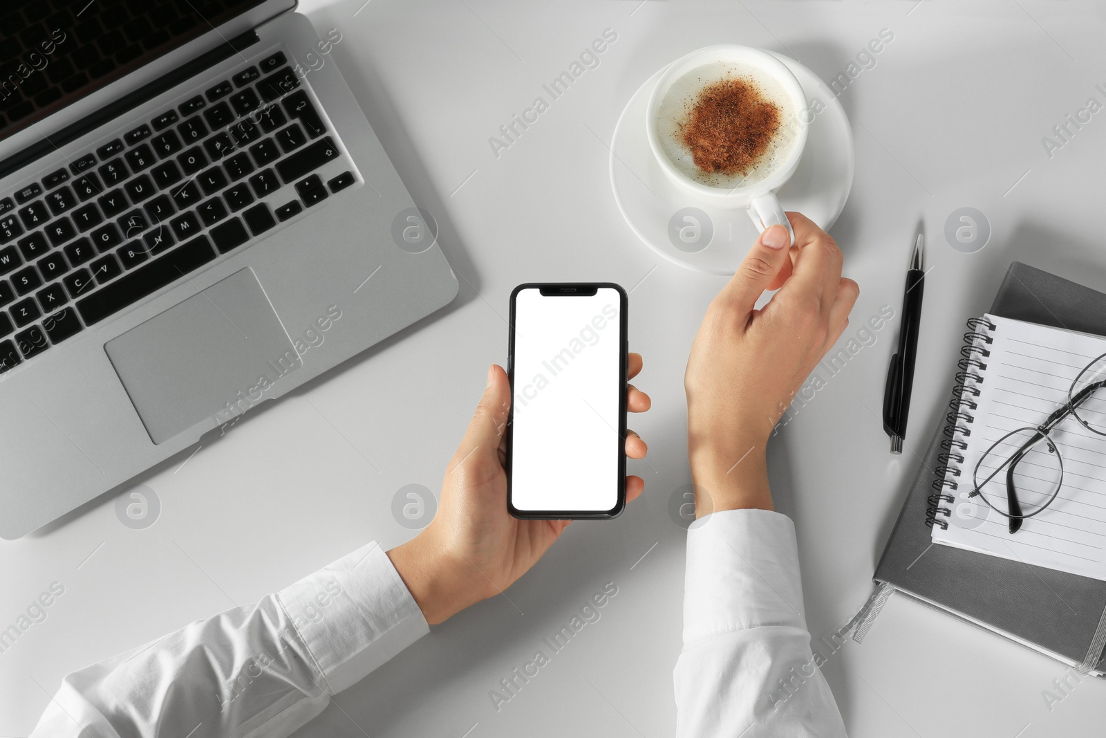 Photo of Woman using smartphone at white table, top view