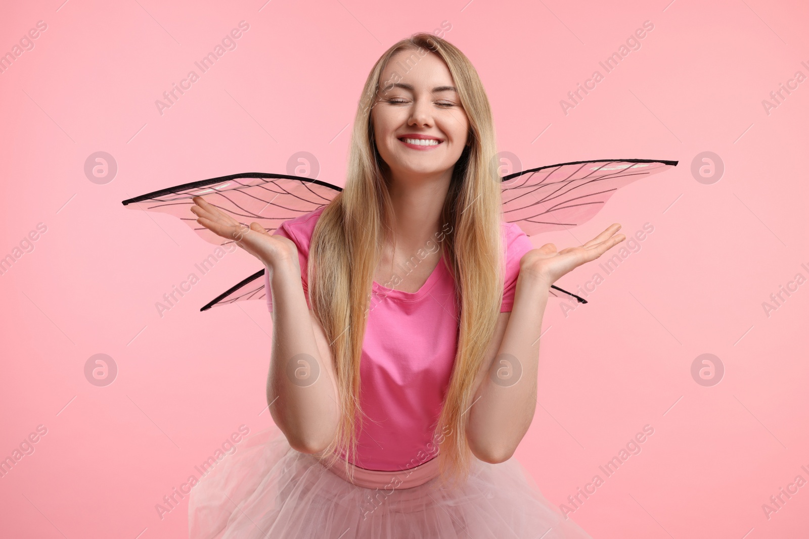 Photo of Beautiful girl in fairy costume with wings on pink background