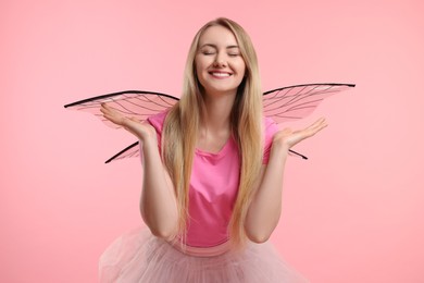 Beautiful girl in fairy costume with wings on pink background