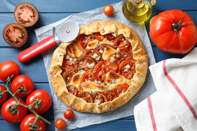 Photo of Flat lay composition of tasty galette with tomato and cheese (Caprese galette) on blue wooden table