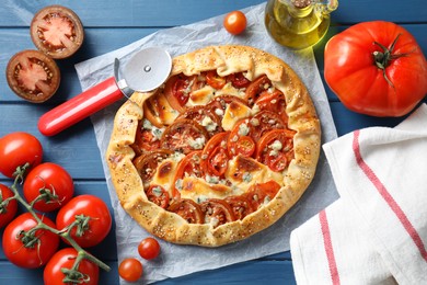 Flat lay composition of tasty galette with tomato and cheese (Caprese galette) on blue wooden table