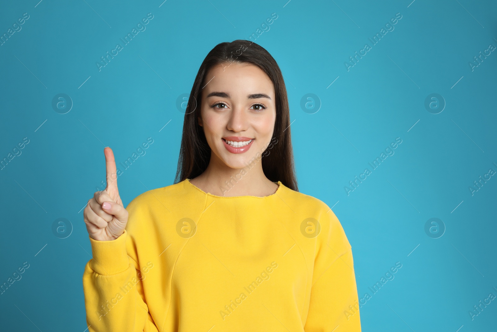 Photo of Woman showing number one with her hand on light blue background