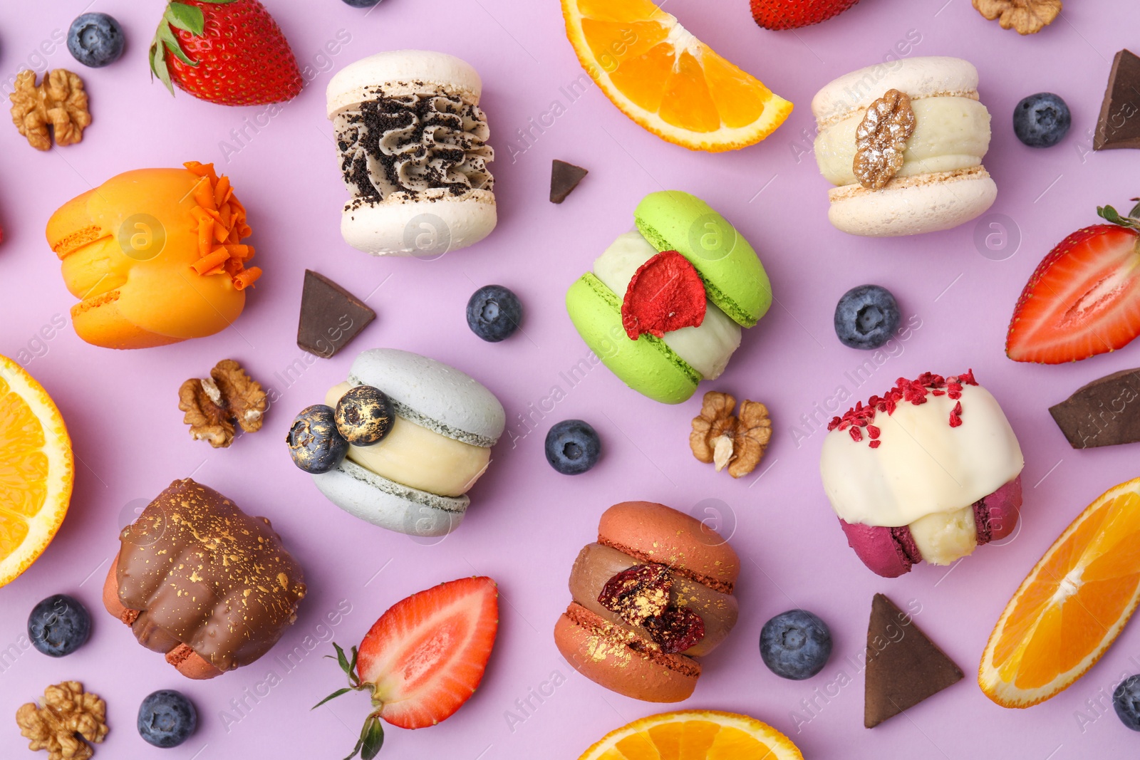 Photo of Delicious macarons, oranges and berries on violet table, flat lay