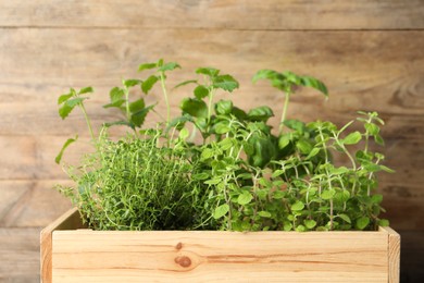 Photo of Crate with different aromatic herbs against wooden background