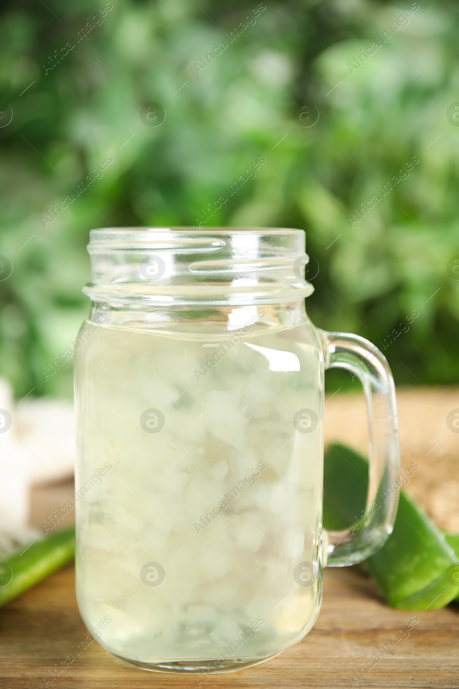 Photo of Fresh aloe drink in mason jar and leaves on wooden table