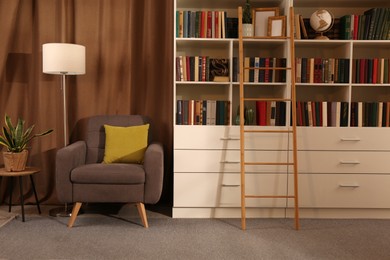 Photo of Cozy home library interior with collection of different books on shelves and comfortable place for reading