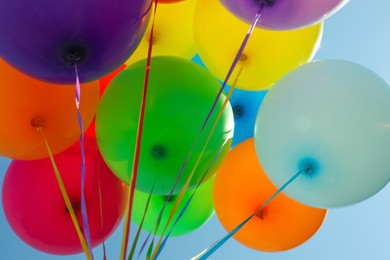 Photo of Bunch of colorful balloons against blue sky, low angle view