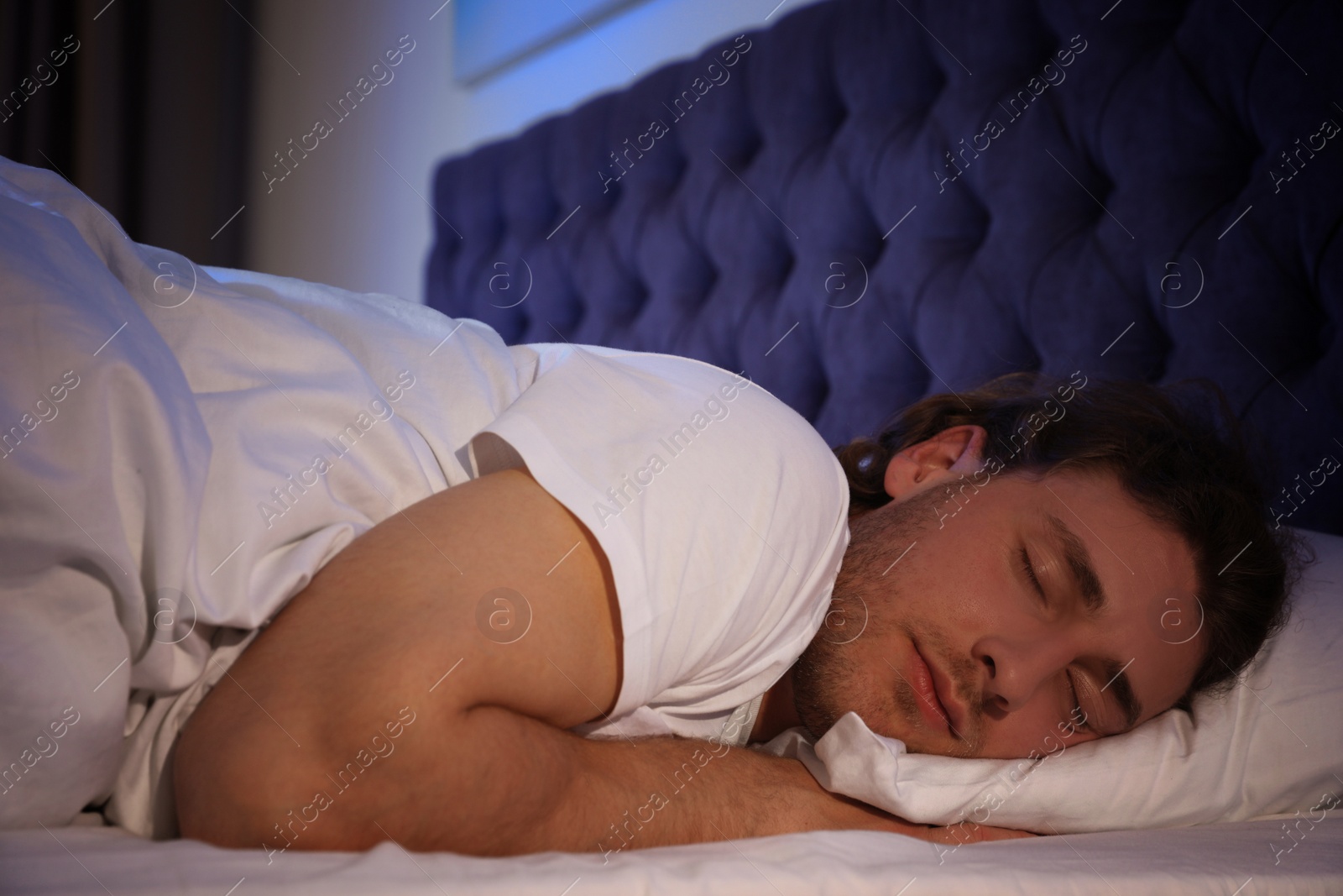 Photo of Handsome young man sleeping on pillow at night. Bedtime