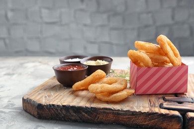 Fried onion rings served with sauces on wooden board