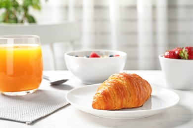 Tasty breakfast with croissant served on white wooden table