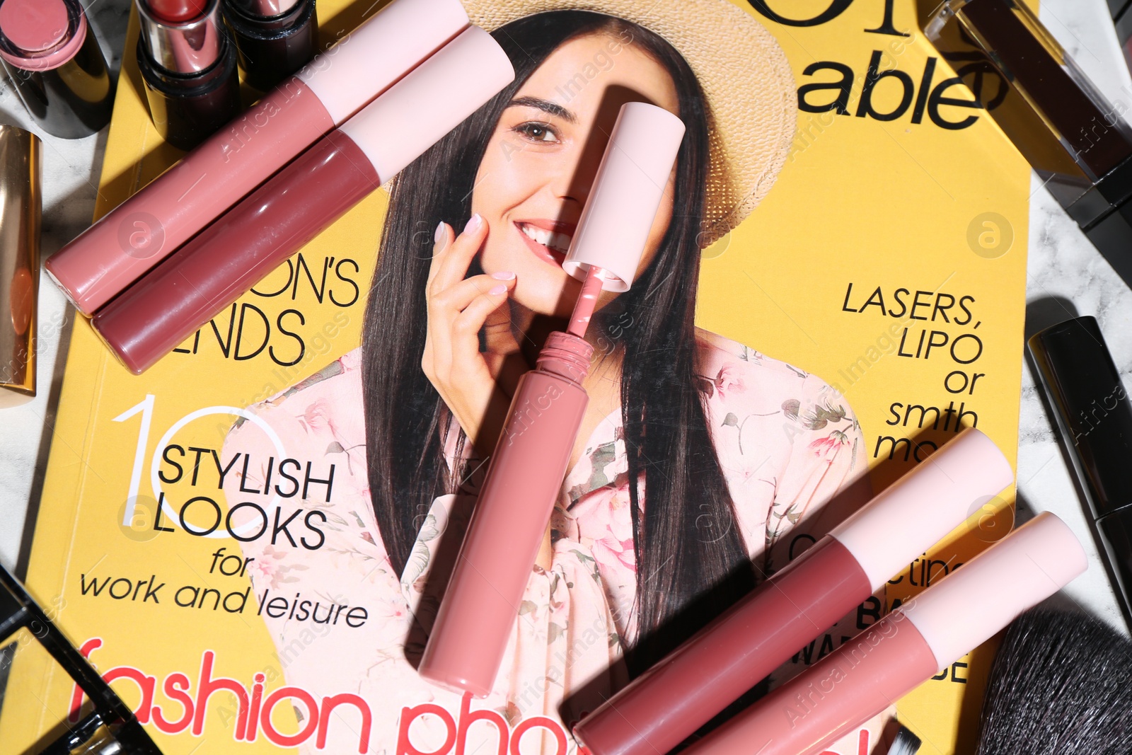 Photo of Bright lip glosses and fashion magazine on table, flat lay