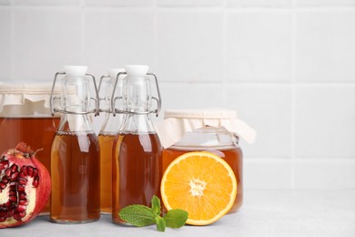 Tasty kombucha, fresh fruits and mint on white table, space for text