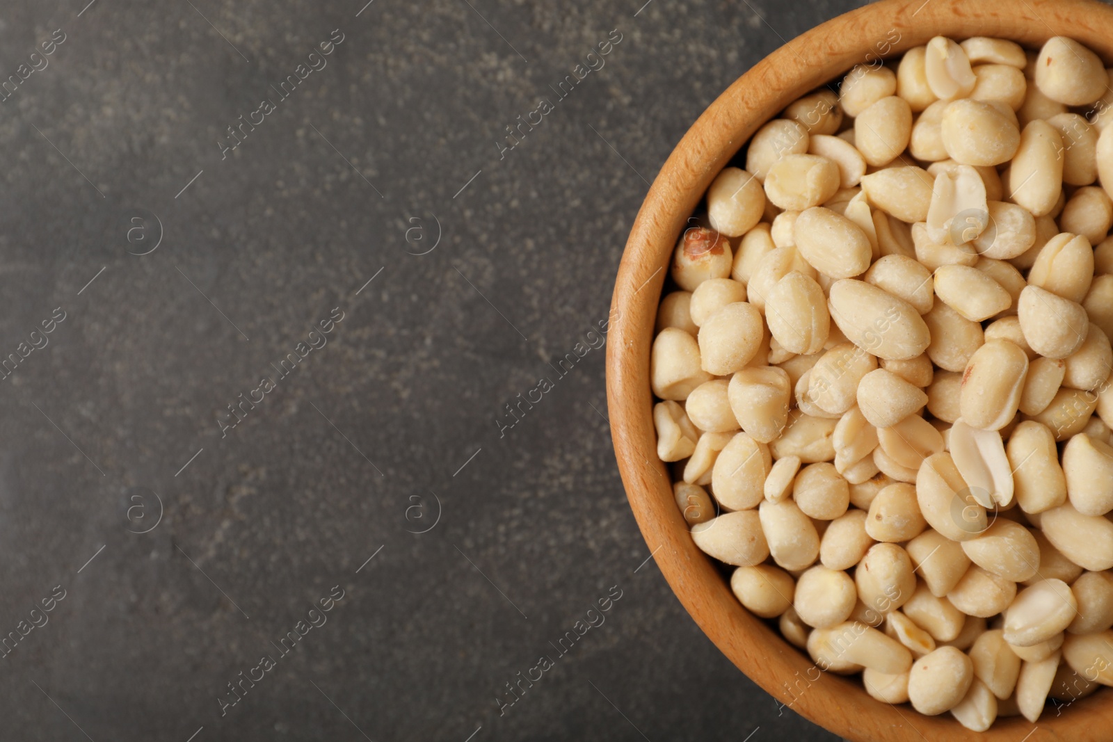 Photo of Shelled peanuts in bowl and space for text on table, top view