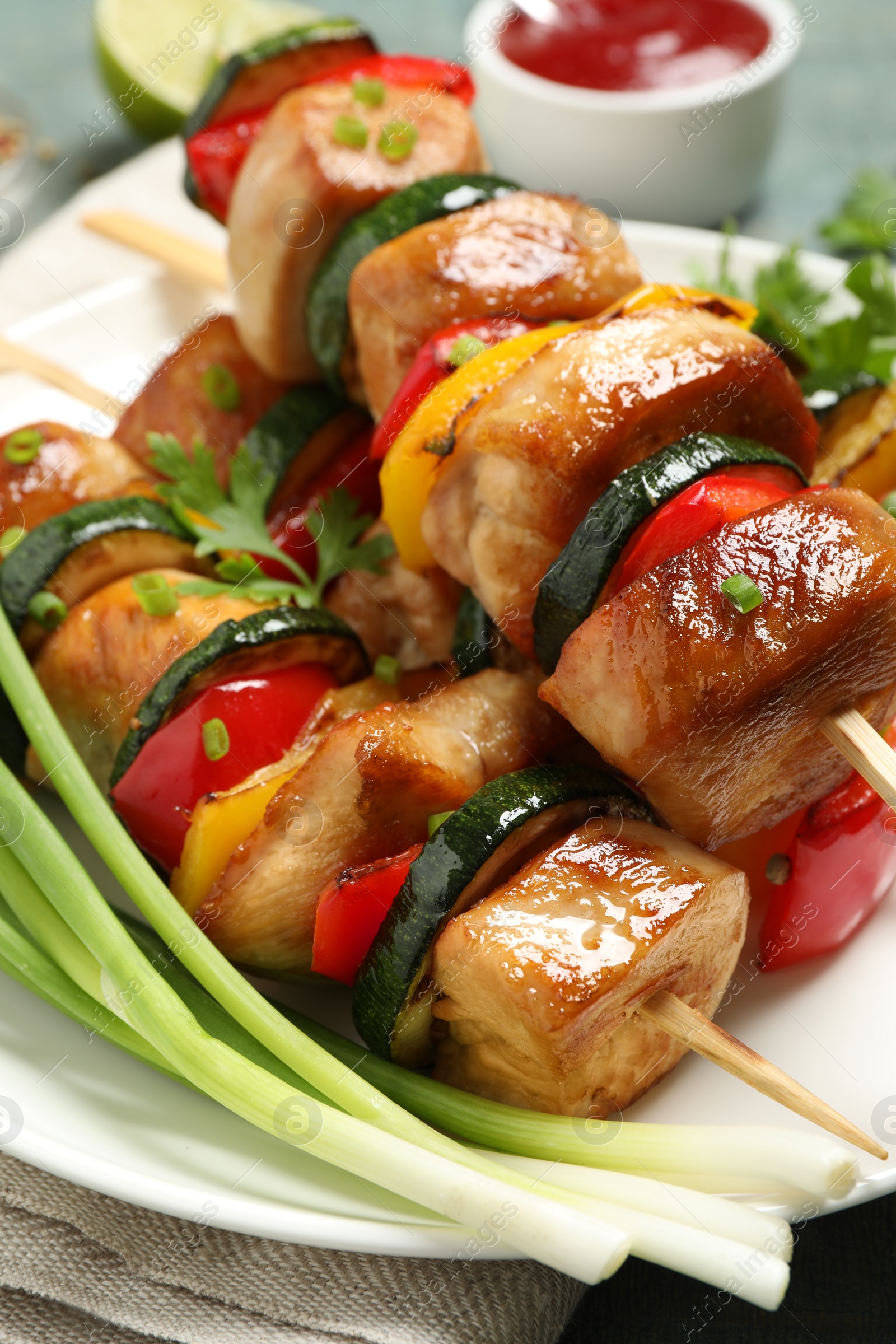 Photo of Delicious chicken shish kebabs with vegetables and parsley on plate, closeup