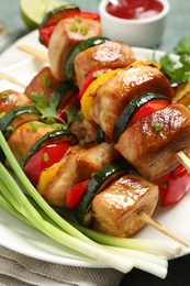 Delicious chicken shish kebabs with vegetables and parsley on plate, closeup