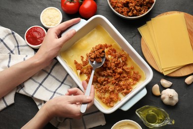 Photo of Woman making lasagna at dark table, top view