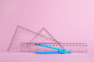 Photo of Different rulers and compass on pink background