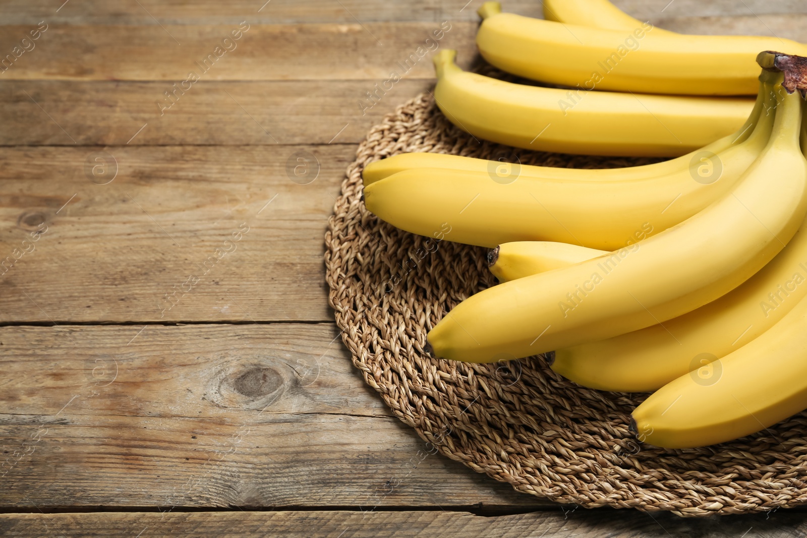 Photo of Ripe sweet yellow bananas on wooden table. Space for text