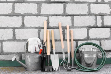 Photo of Set of gardening tools near brick wall