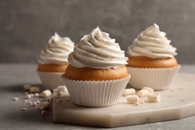 Photo of Delicious cupcakes decorated with cream on light grey table