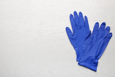 Pair of medical gloves on white wooden background, flat lay. Space for text