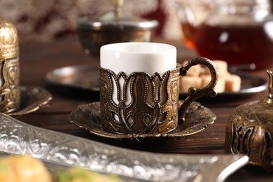 Photo of Traditional Turkish tea served in vintage tea set on wooden table, closeup