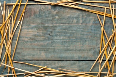Photo of Frame of dried hay on light blue wooden background, flat lay. Space for text