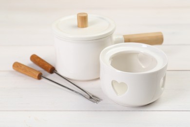 Photo of Fondue set on white wooden table, closeup