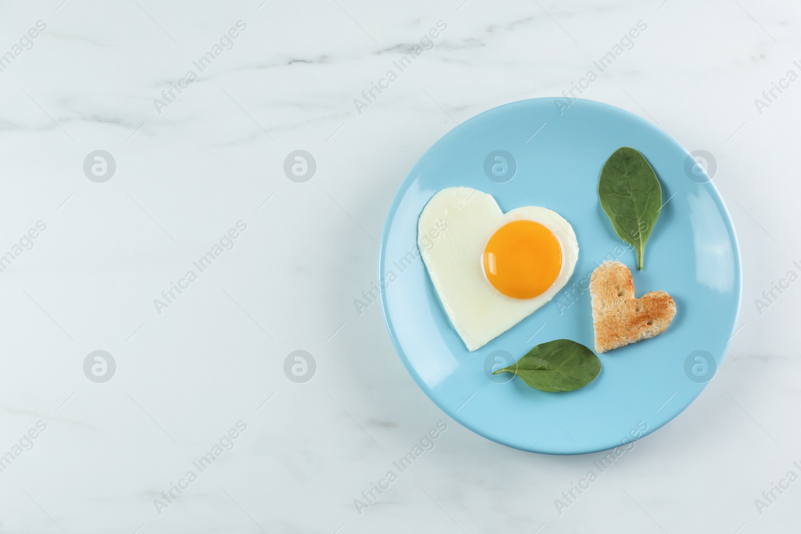 Photo of Romantic breakfast with heart shaped fried egg and toast on white marble table, top view. Space for text