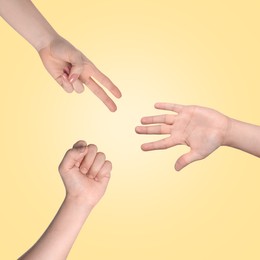 People playing rock, paper and scissors on yellow background, top view