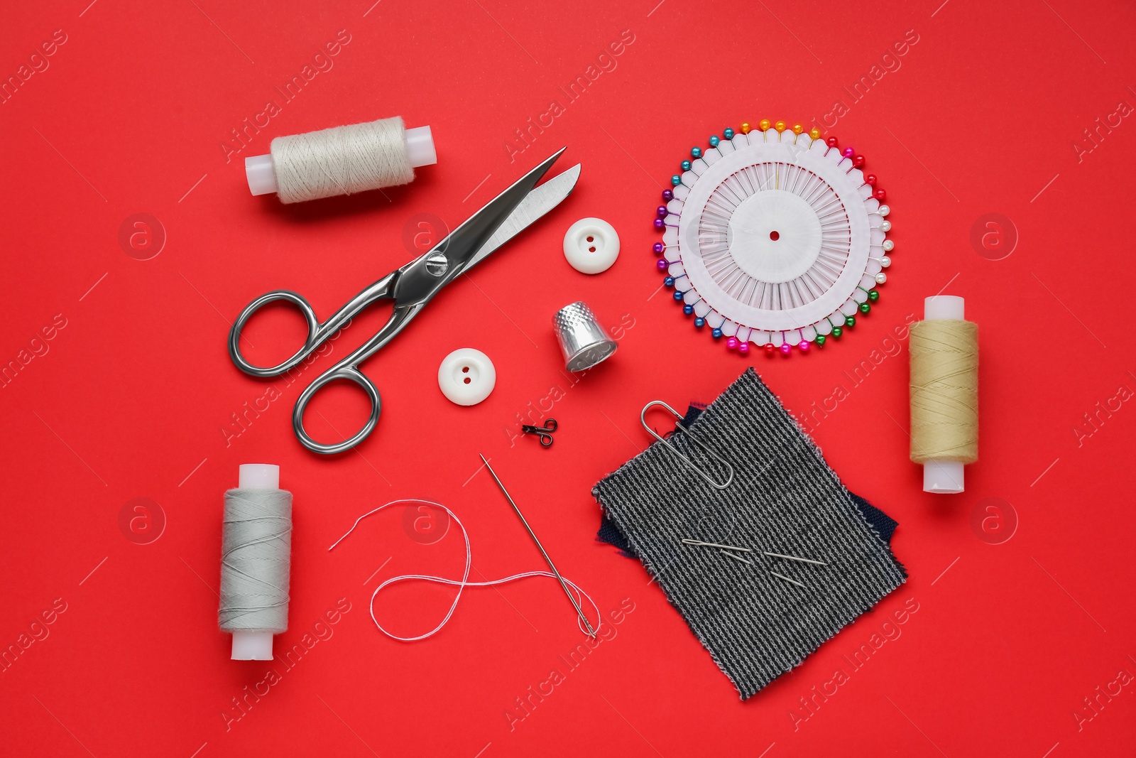 Photo of Flat lay composition with thimble and different sewing tools on red background