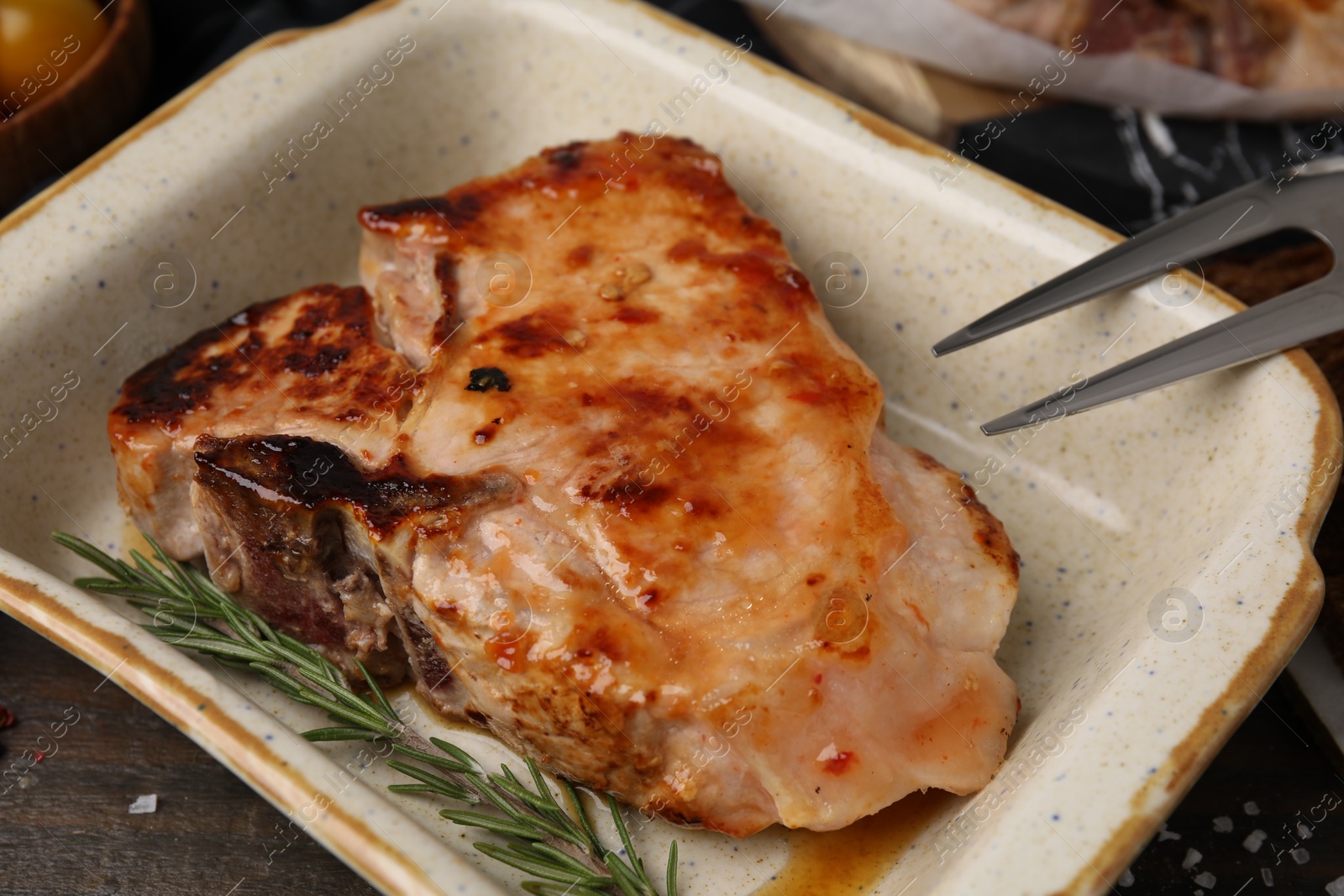 Photo of Tasty marinated meat and rosemary in baking dish on wooden table, closeup