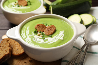 Photo of Tasty homemade zucchini cream soup served on table