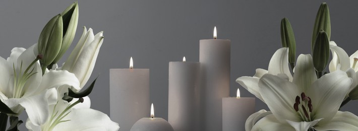 Image of Funeral. Burning candles between white lilies on grey background, banner design